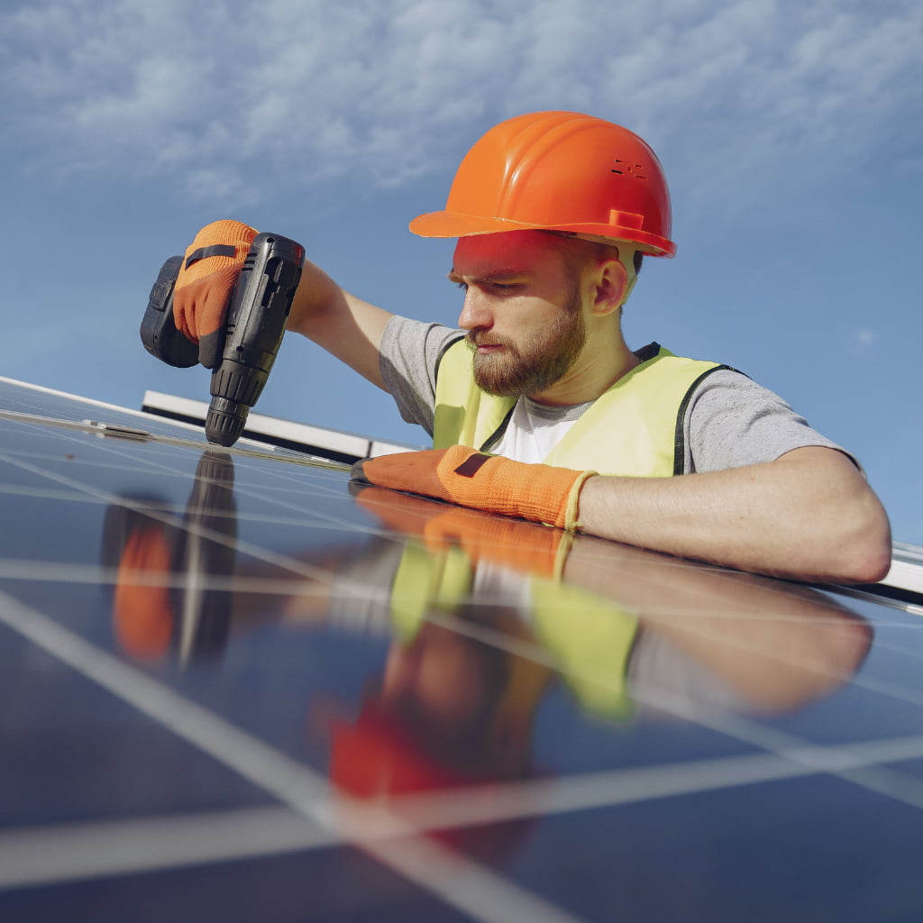 Worker fixing solar panels to a roof